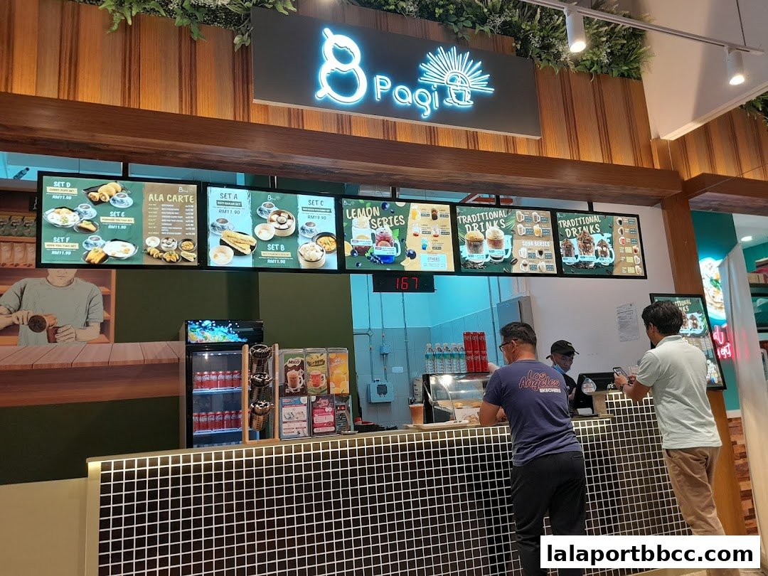 A food counter with digital menus displaying food sets and drinks, and customers ordering.