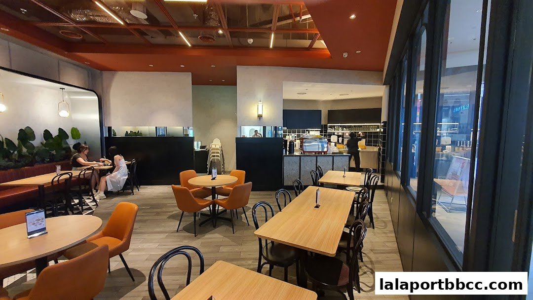 Interior view of a modern cafe with tables, chairs, and a counter area.