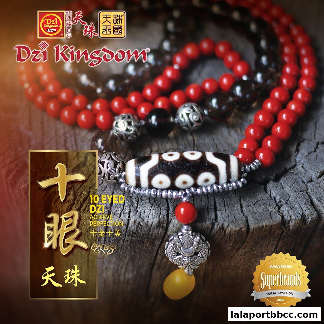 A close-up of a Dzi bead bracelet with red and black beads, featuring a 10-eyed Dzi bead.