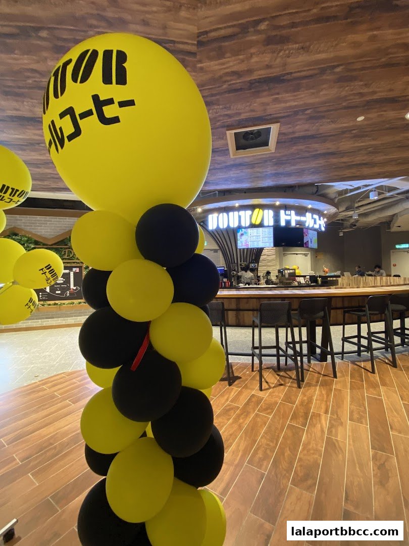 A column of yellow and black balloons with the shop's logo in front of a coffee shop counter.