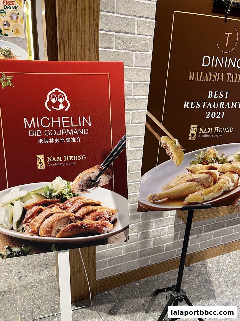 Signs showcasing Michelin Bib Gourmand and Best Restaurant awards for Nam Heong Chicken Rice.