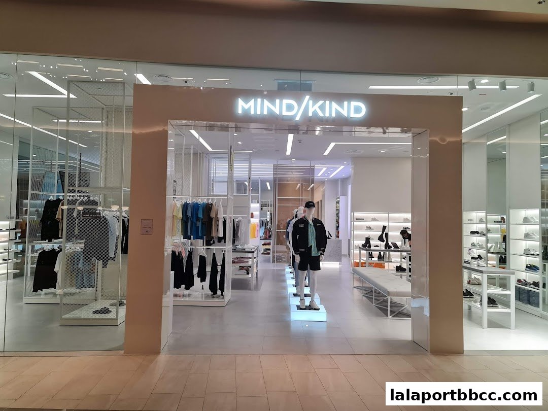 The entrance of a modern clothing store with mannequins and apparel displayed inside.