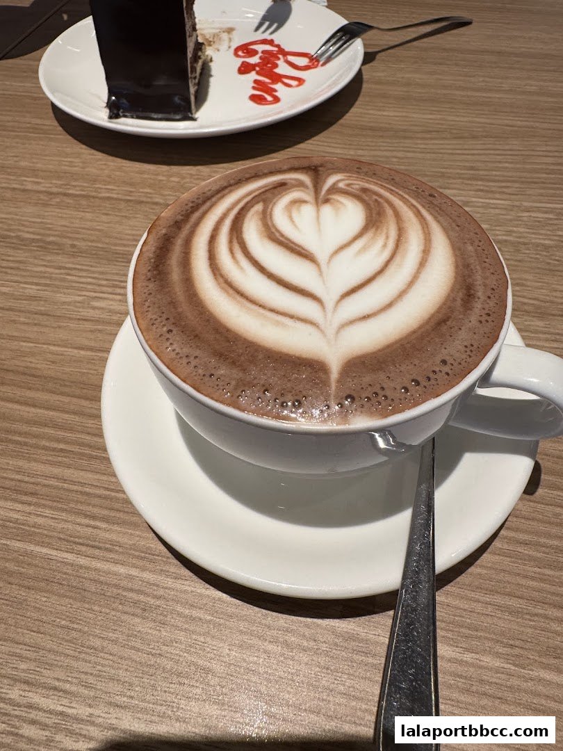 A close-up of a latte with heart art and a slice of chocolate cake.