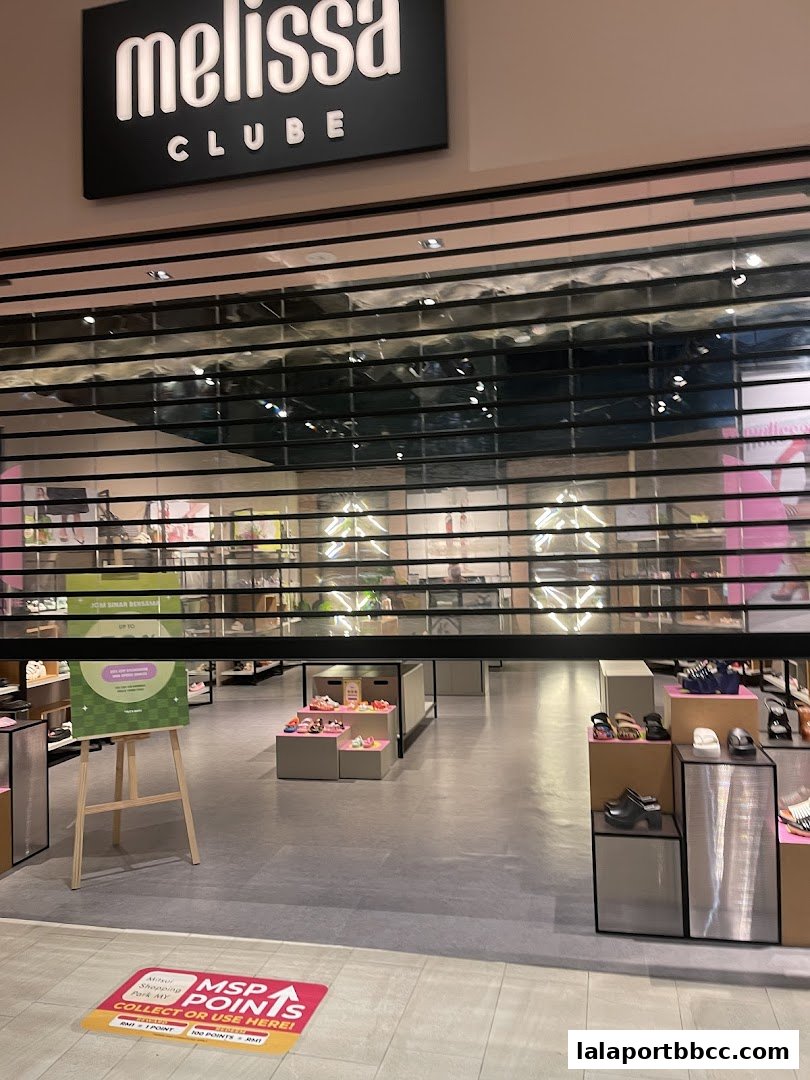 The Clube Melissa shop entrance with the roller shutter partially down, displaying shoes inside.