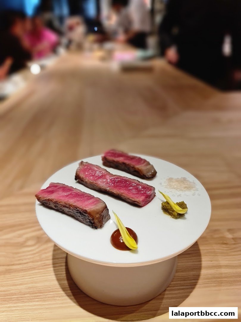 A white plate with three slices of perfectly cooked steak, garnished with sauce and herbs.
