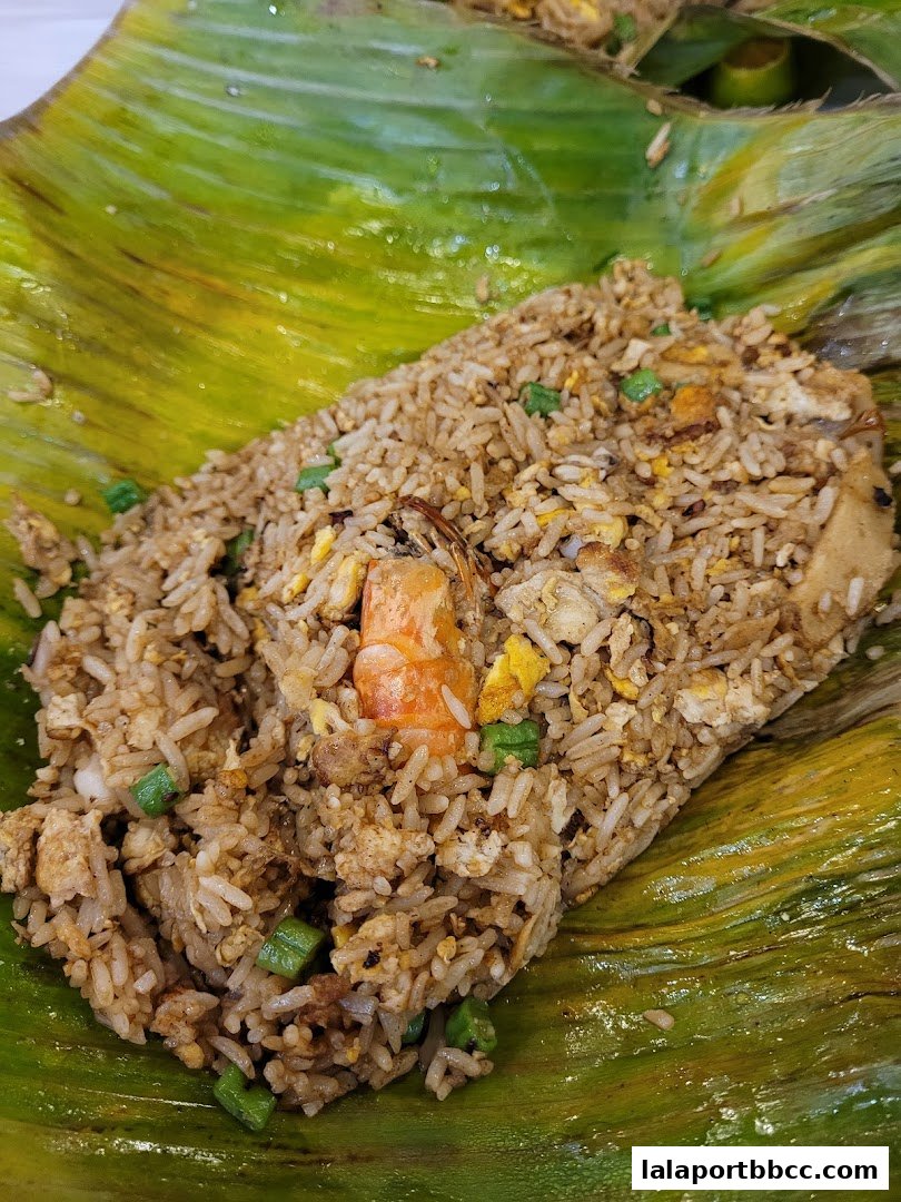 A close-up shot of delicious fried rice served on a banana leaf with shrimp and vegetables.