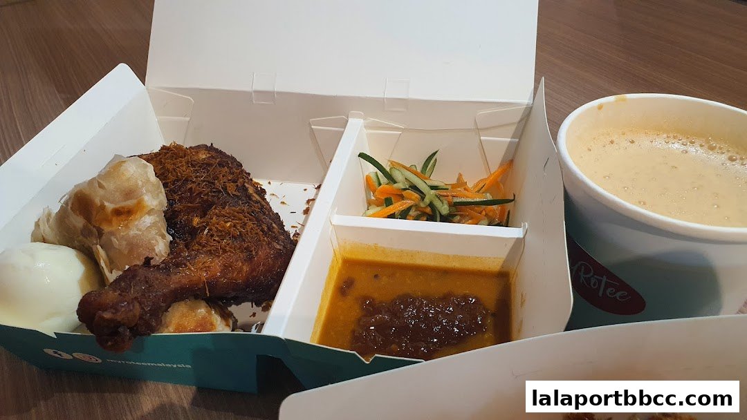 A takeaway box filled with fried chicken, roti, rice, salad, and curry, alongside a cup of coffee.