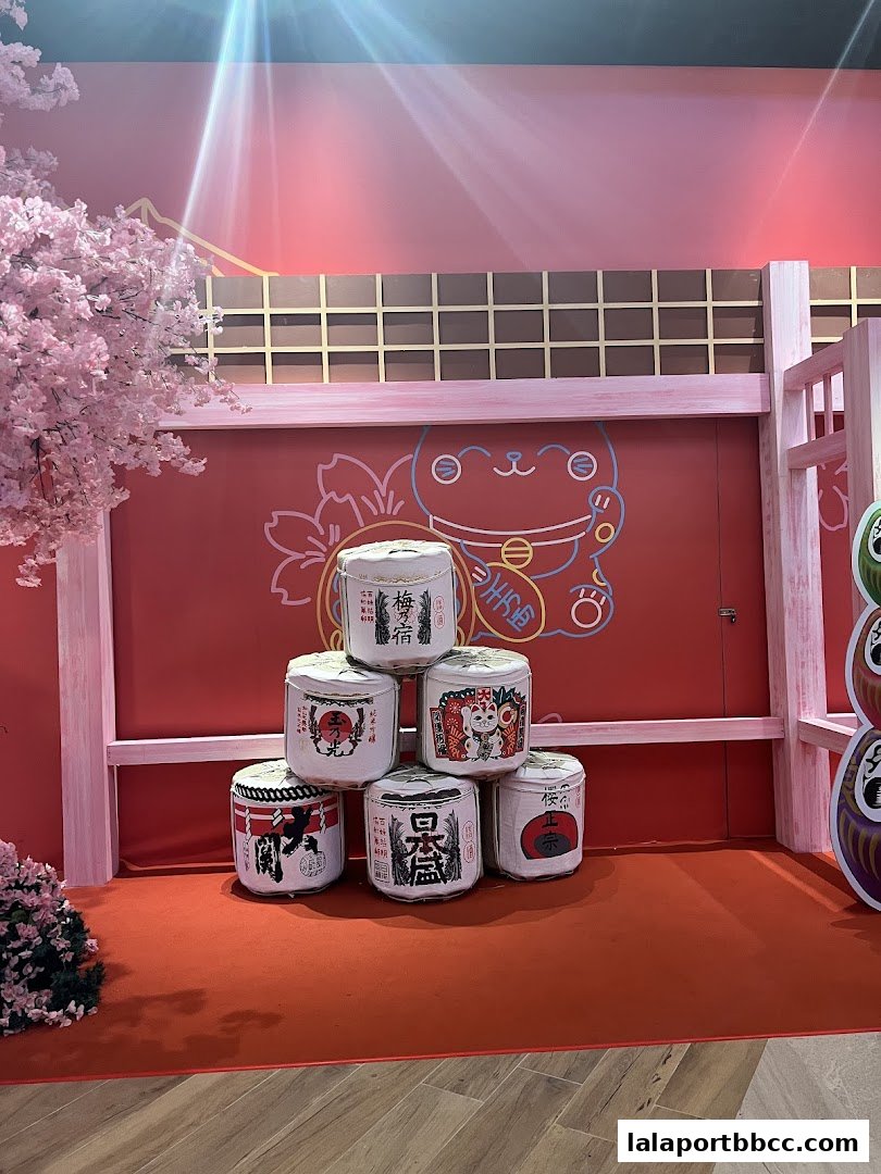 A display of Japanese sake barrels and cherry blossoms with a Maneki-neko illustration.