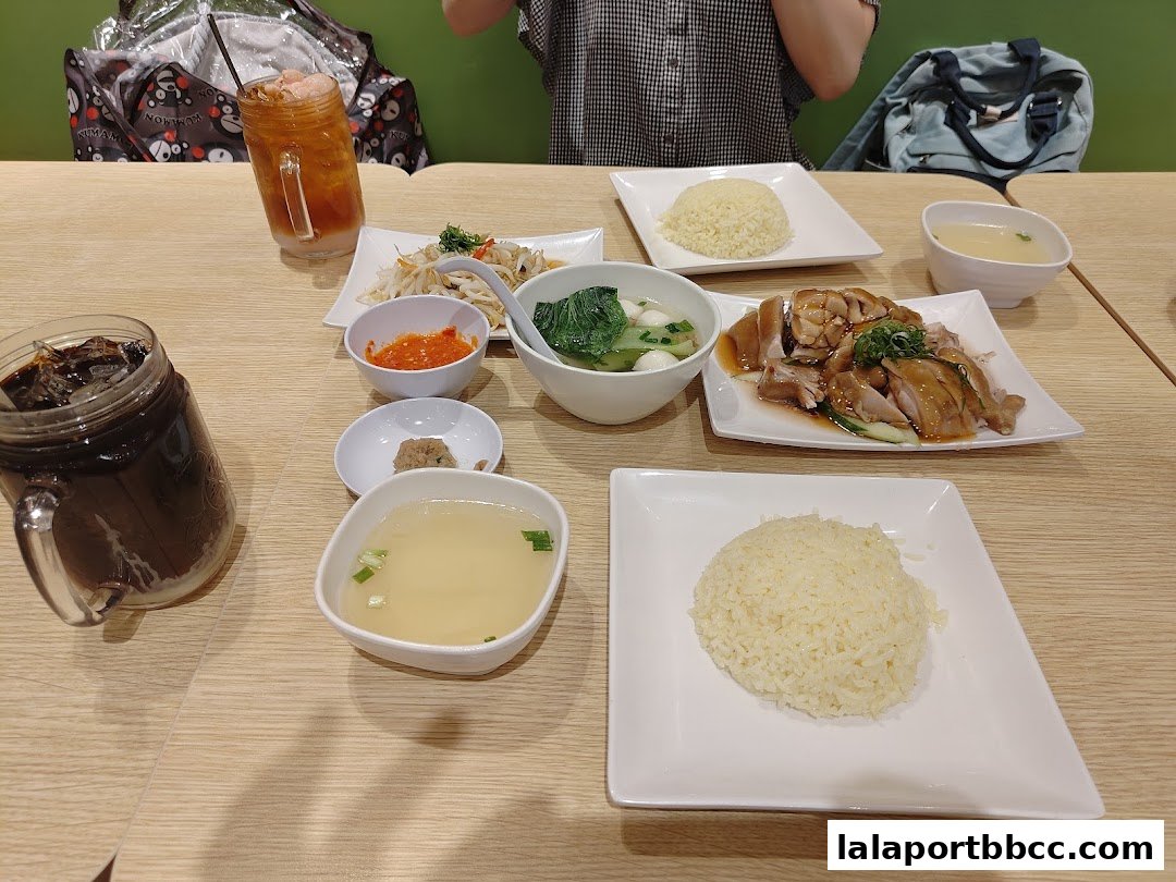 A table laden with delicious chicken rice meals, soup, and drinks.