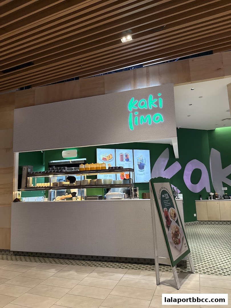 The Kaki Lima Corner shop front with a menu board and illuminated signage.