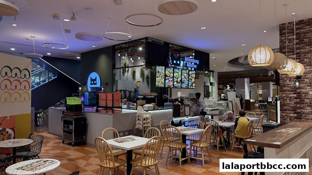 Interior view of a brightly lit cafe with seating, a counter, and digital menus.