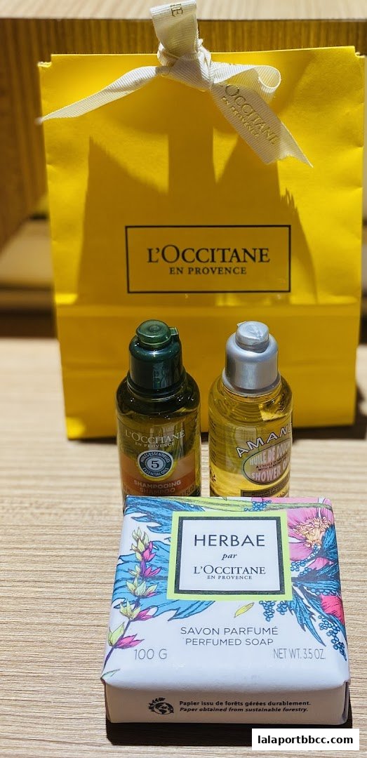 L'Occitane products including a yellow gift bag, shampoo, shower oil, and perfumed soap.