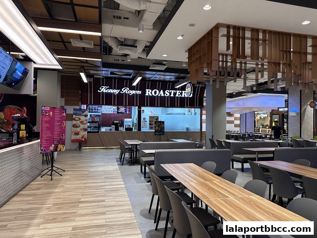 Interior view of a dining area with tables and chairs, and a Kenny Rogers Roasters restaurant.