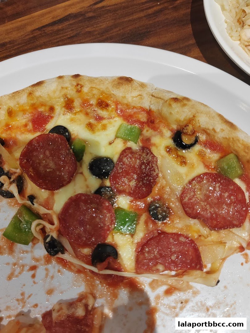 A close-up shot of a delicious slice of pepperoni pizza with olives and peppers.