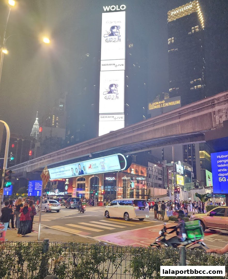 A busy city street at night with tall buildings, traffic, and illuminated signs.
