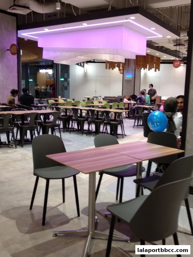 Interior view of a modern cafeteria with tables, chairs, and people dining.