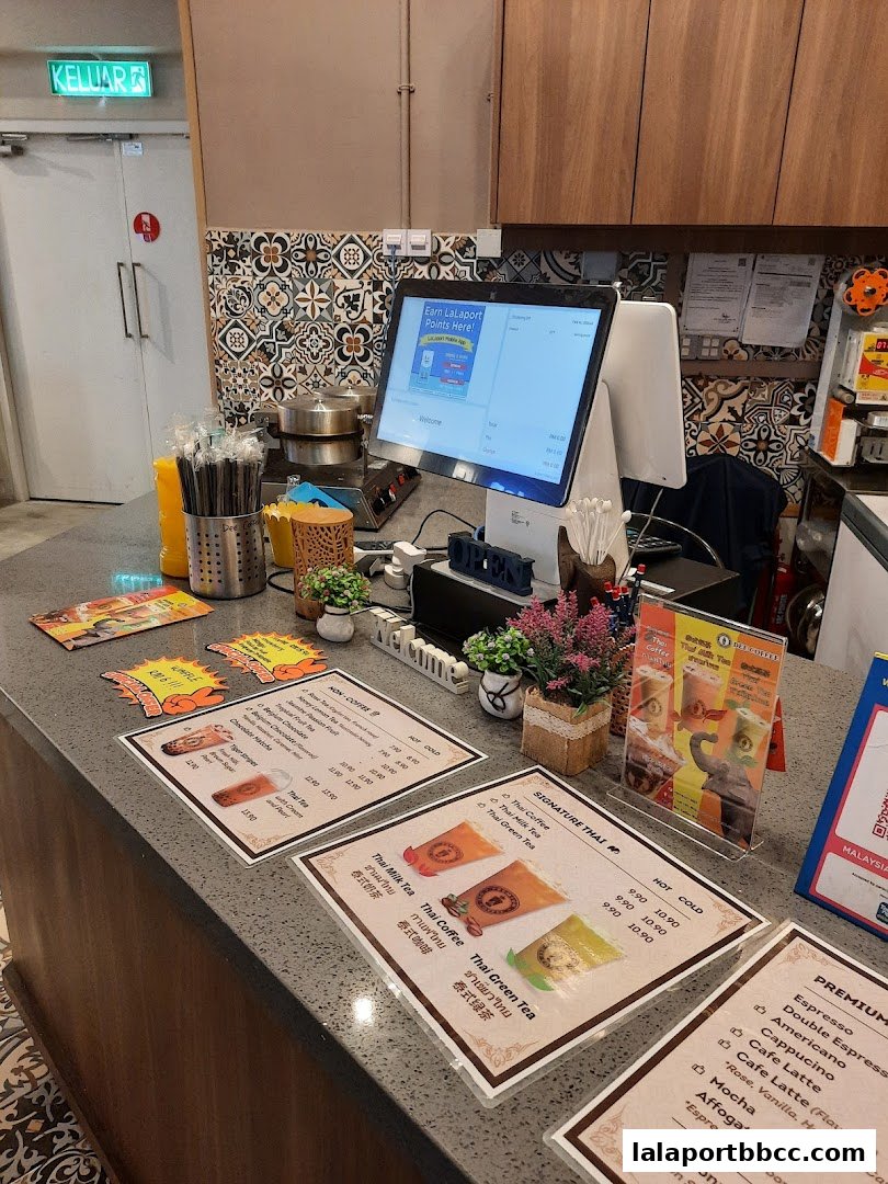 A counter at Dee Coffee Malaysia with menus, a POS system, and coffee-making equipment.
