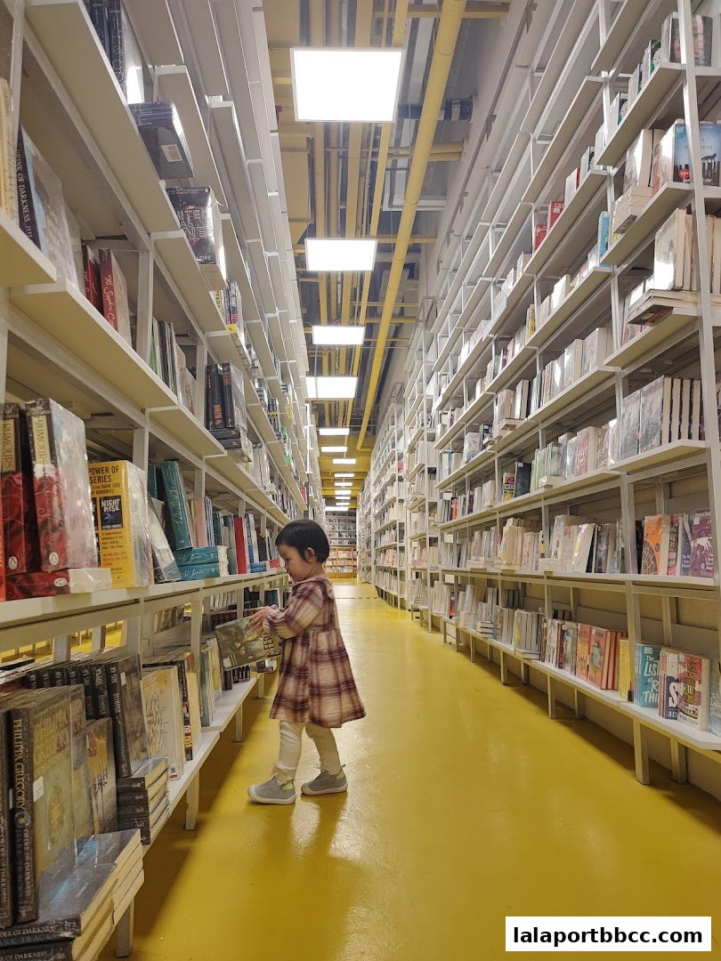 A young child browses books in a brightly lit bookstore with tall shelves.