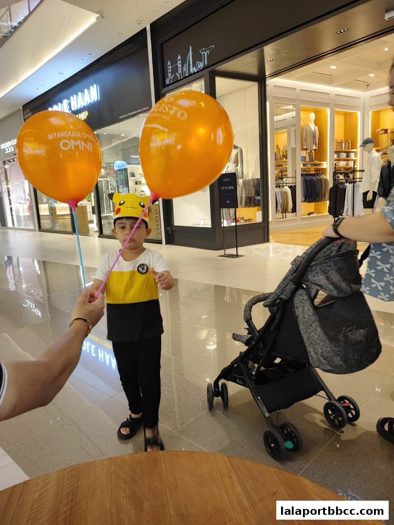 A child holding balloons in front of a shop with a sale sign.