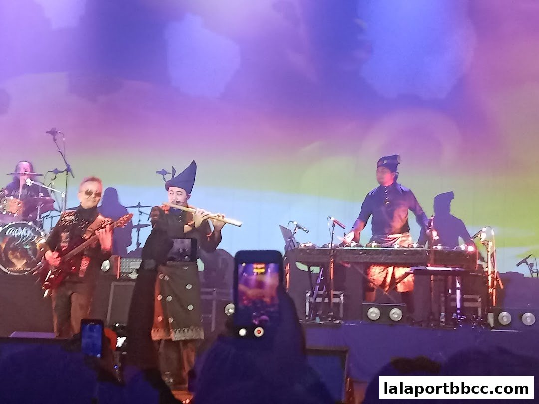 A band performs on stage with musicians playing guitars, drums, and traditional instruments.