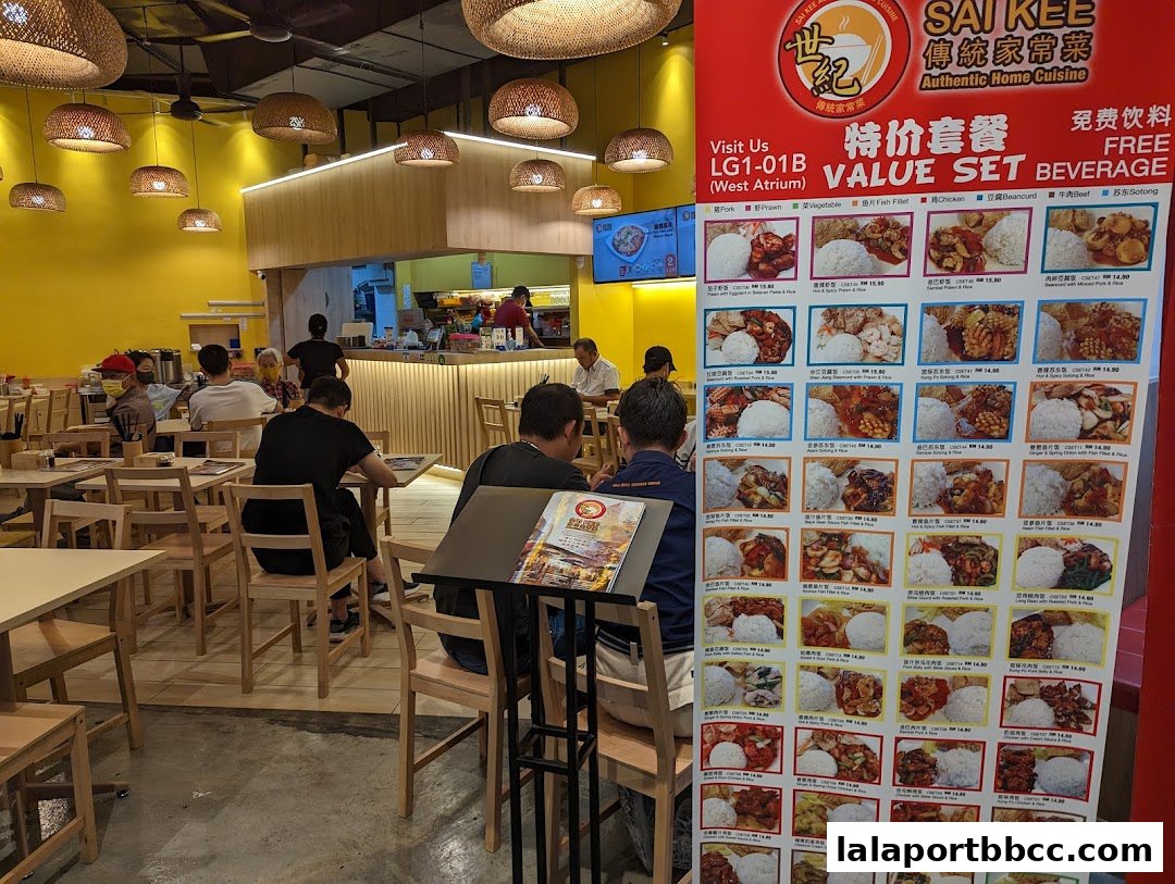 Interior of a restaurant with customers seated and a large menu board displaying food.
