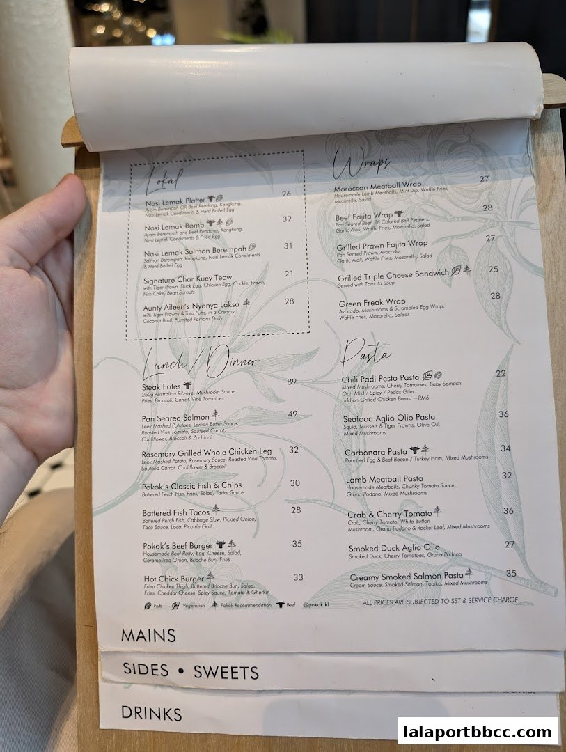 A person's hand holding a menu with various food and drink options listed.