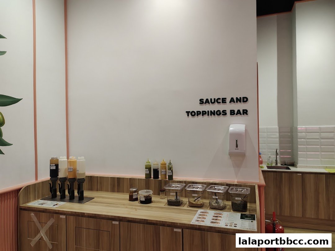 A sauce and toppings bar with various dispensers and containers of ingredients.