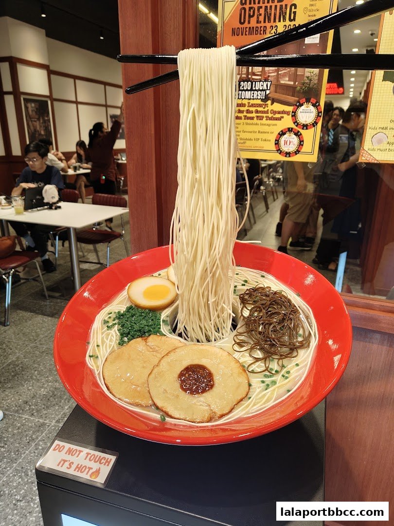 A realistic ramen display with chopsticks holding noodles above a bowl.