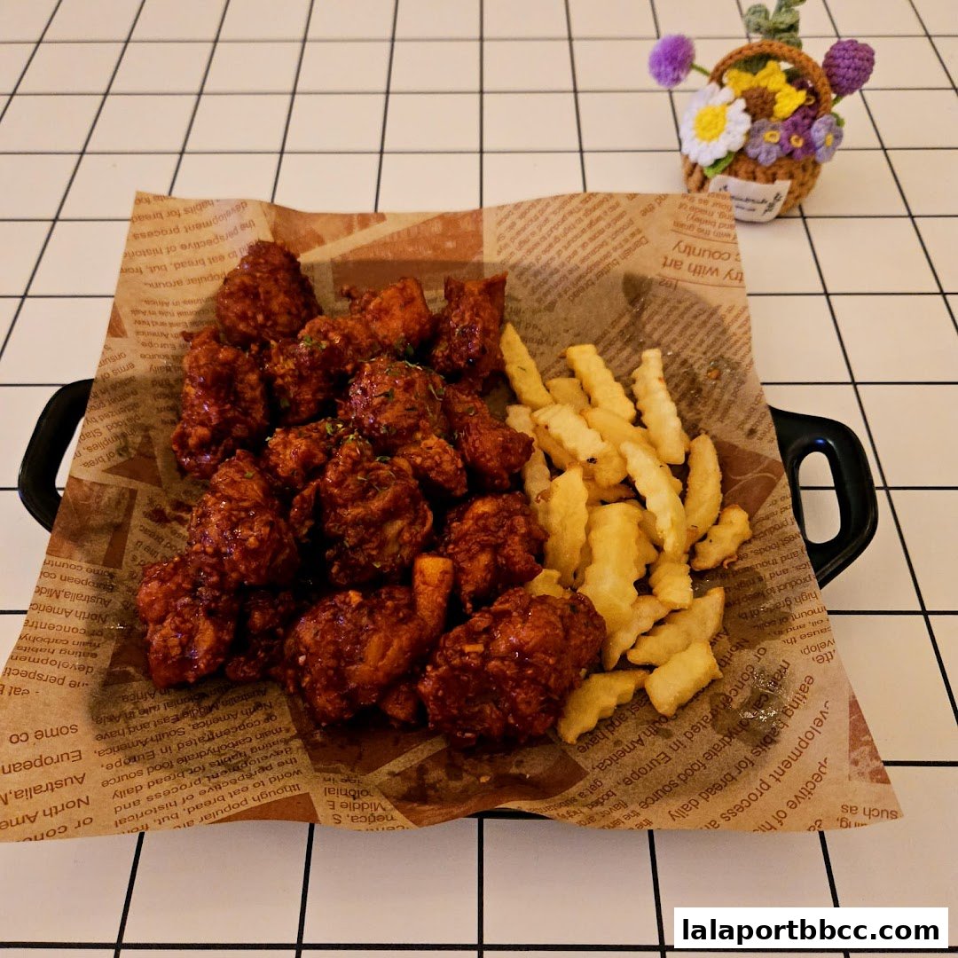 A serving of crispy fried chicken pieces with french fries on a newspaper-lined tray.