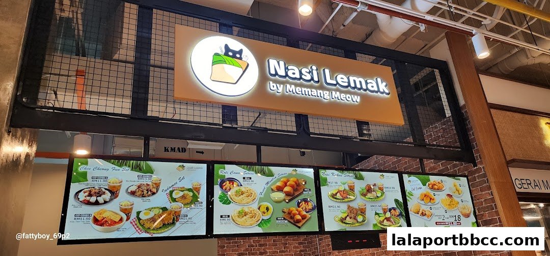 A food court stall sign with illuminated menus displaying various Malaysian dishes.