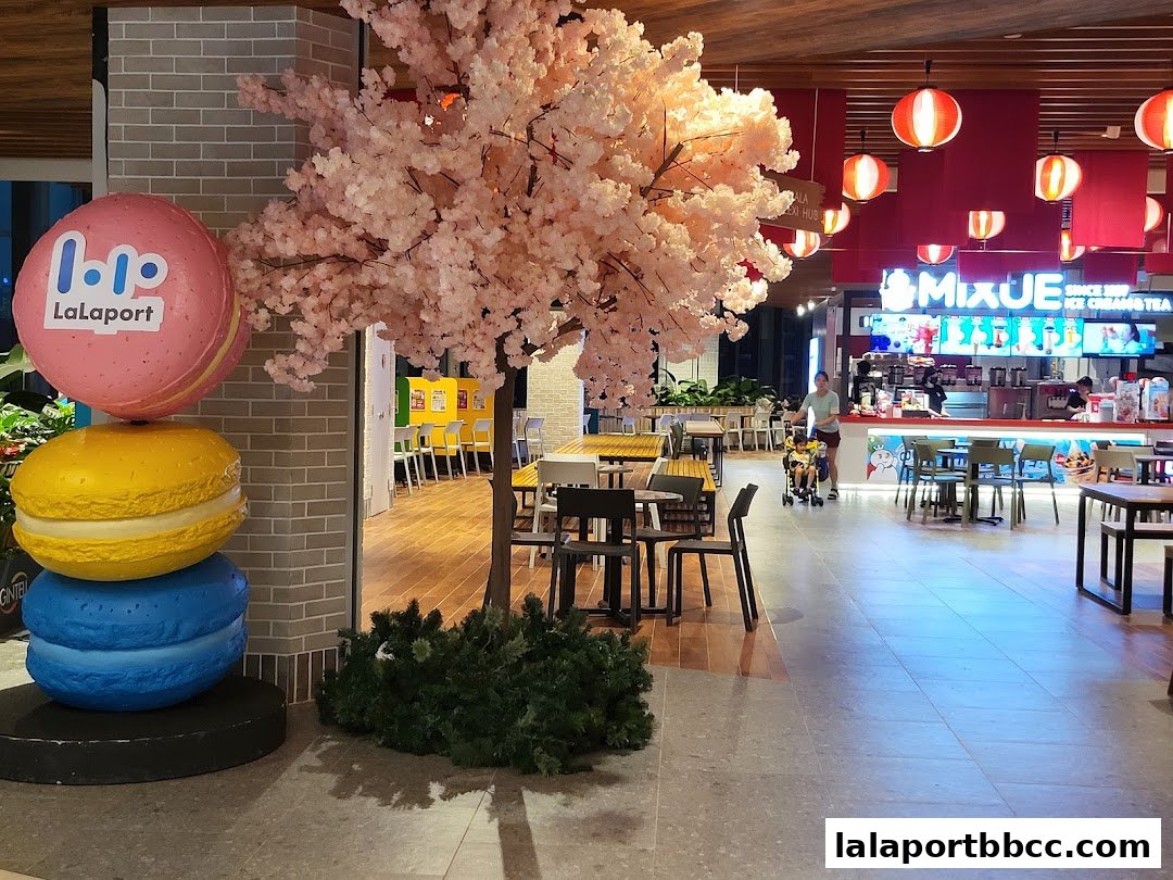 A view of the MIXUE ice cream and tea shop entrance with decorative macarons and a cherry blossom tree.