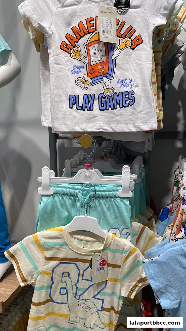Children's t-shirts and shorts with playful graphics displayed on hangers.