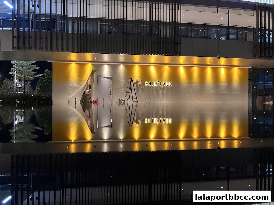 The illuminated storefront of ShinLabo by James Won reflects in the water at night.