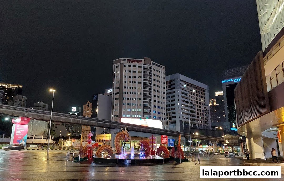 Night view of a city square with dragon decorations and a fountain.