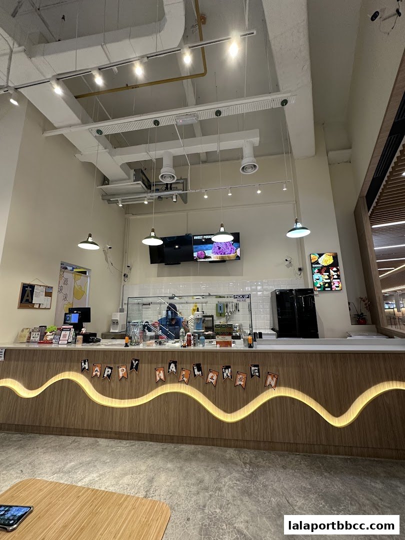 A clean and modern dessert shop counter with a Halloween banner and digital menu displays.