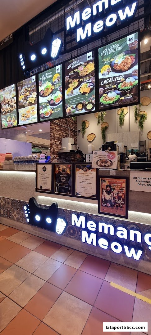 A brightly lit food stall with illuminated signage and a menu displaying various dishes.