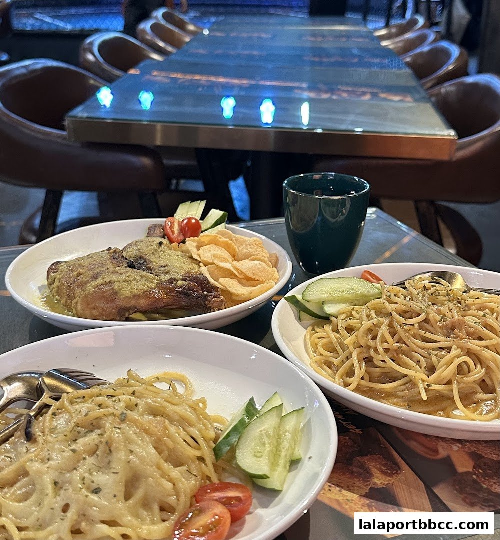 Three plates of food, including pasta and a meat dish, are arranged on a table with chairs.