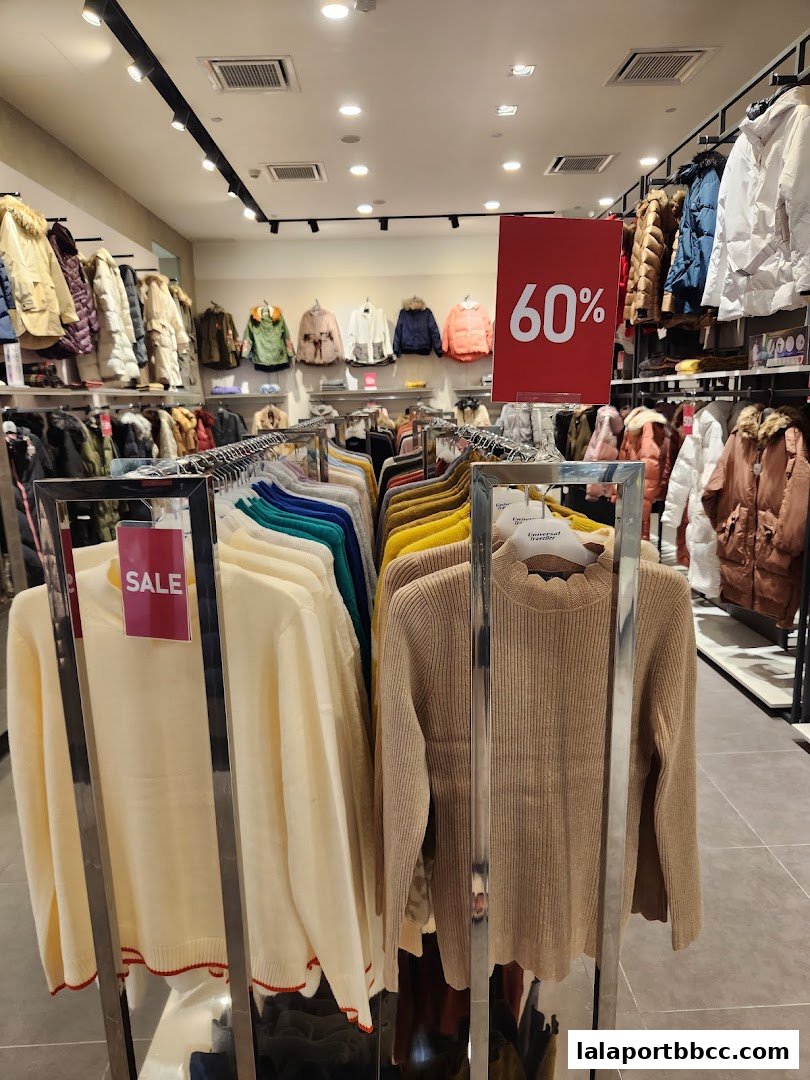 Interior view of a clothing store with racks of sweaters and jackets, featuring a 60% off sale sign.