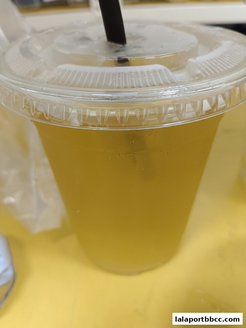 A close-up of a refreshing yellow beverage in a clear plastic cup with a straw.