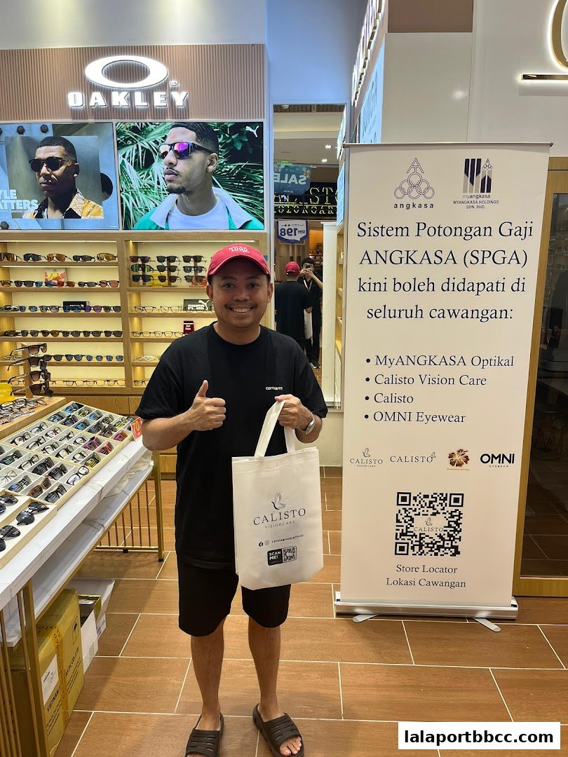A man gives a thumbs up in front of a Calisto Vision Care store displaying Oakley sunglasses.