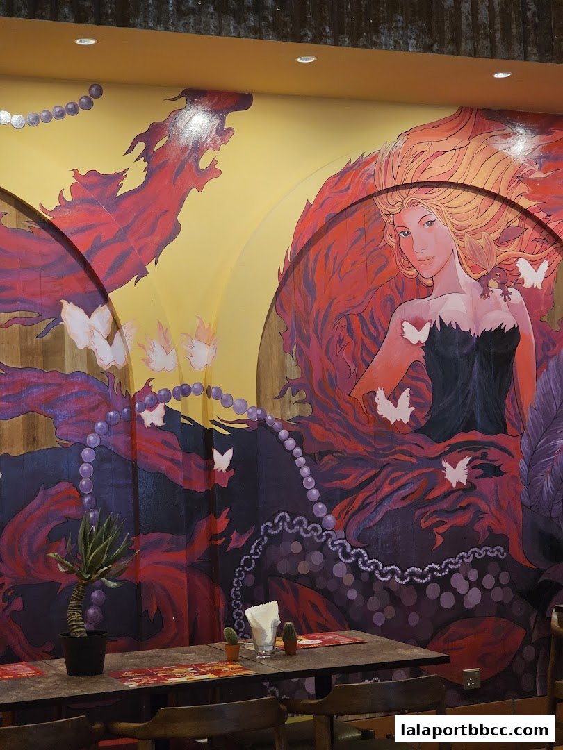 A vibrant mural of a woman with flowing red hair and butterflies adorns a restaurant wall.