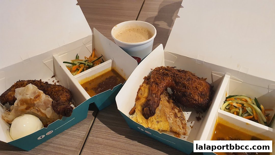Two takeaway boxes filled with fried chicken, roti, rice, salad, and curry, alongside a cup of coffee.