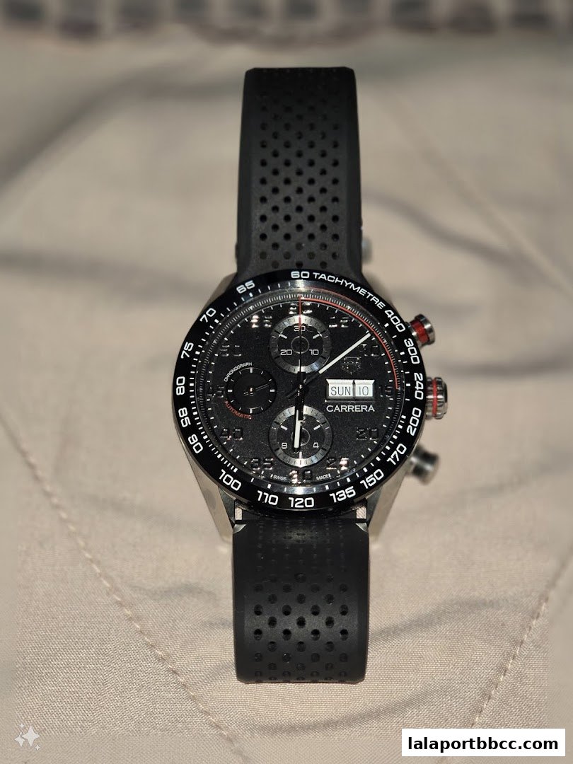 A close-up shot of a black TAG Heuer Carrera chronograph watch with a perforated rubber strap.