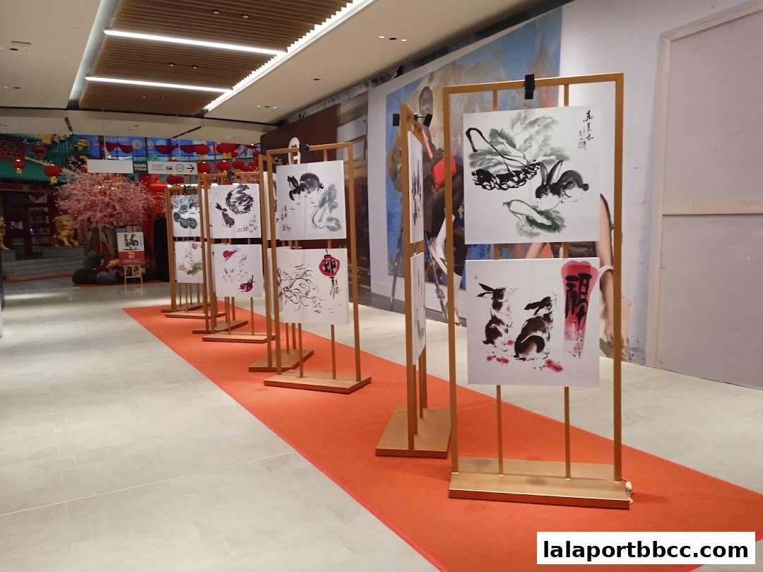 An art exhibition featuring traditional Chinese ink paintings of rabbits and calligraphy displayed on stands.