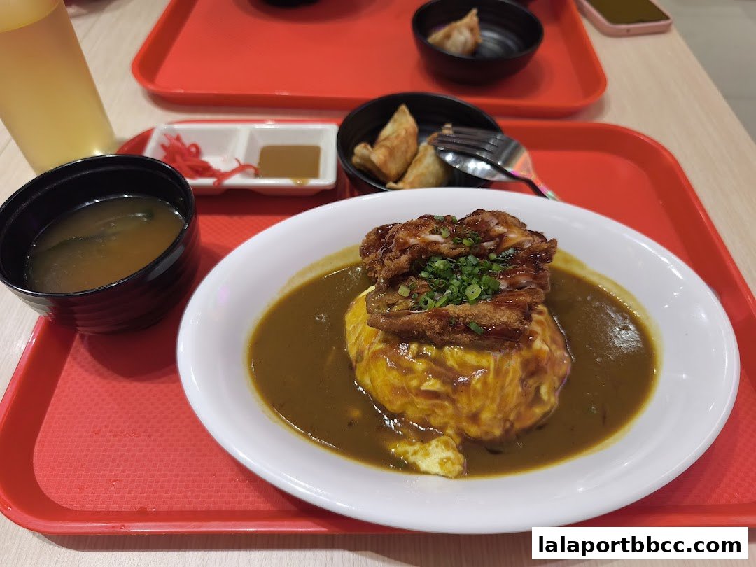 A delicious Japanese curry dish with fried chicken, omelet, and miso soup.