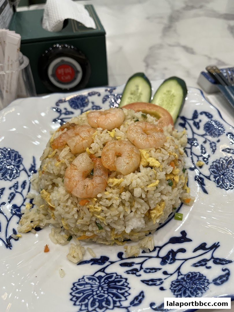 A plate of shrimp fried rice garnished with cucumber and tomato slices.