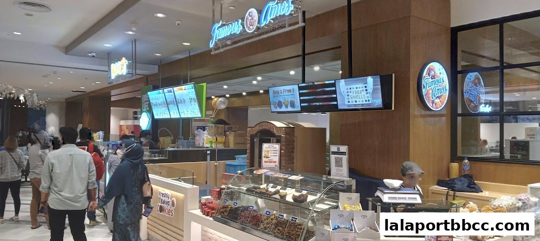 A food stall with a display of cookies and a neon sign for 'Famous Amos'.