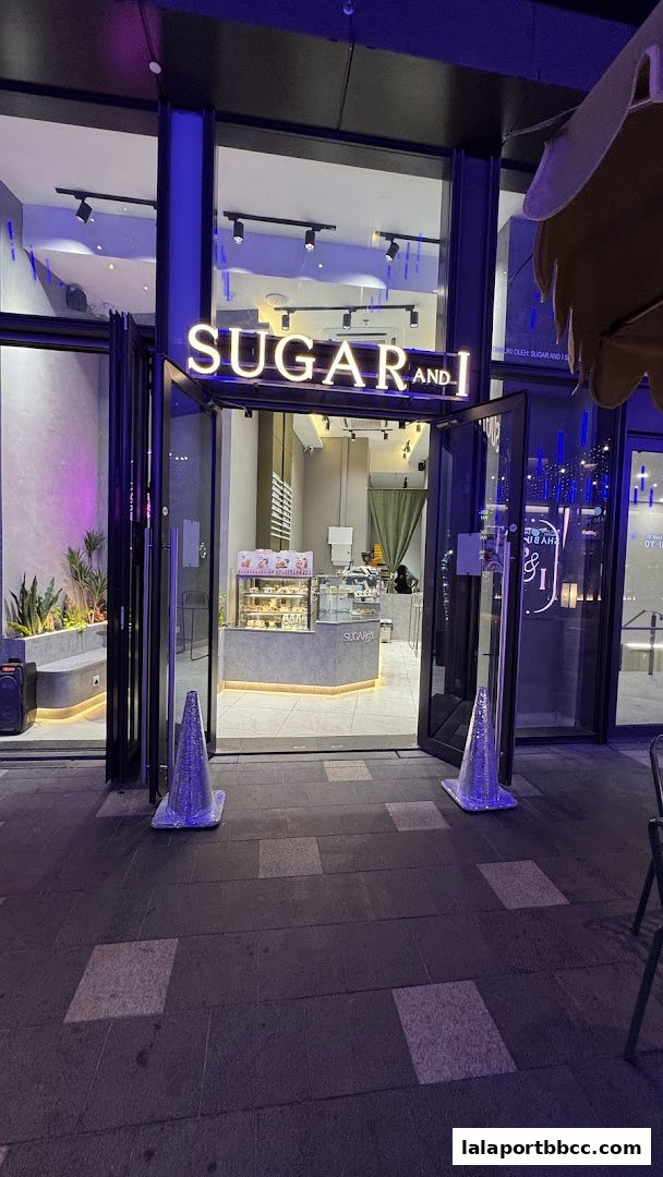 The illuminated storefront of Sugar and I, a dessert shop, at night.