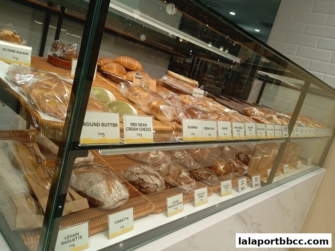 A display case filled with various freshly baked breads and pastries at Daily ButterJaya Grocer.