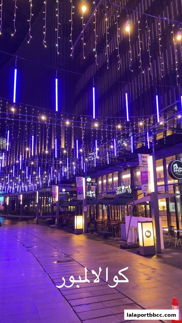 A beautifully lit walkway at night with string lights and blue neon tubes.